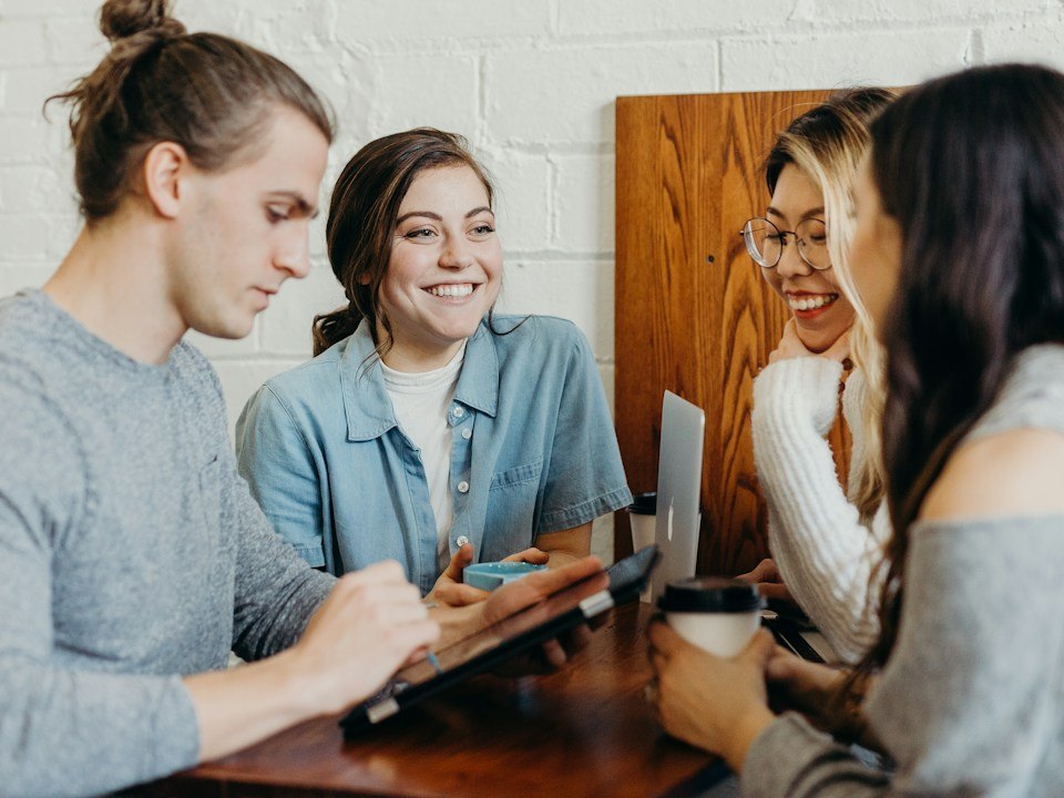 Grupo de estudiantes sonrientes compartiendo material en una mesa; fotograf�a ilustrativa